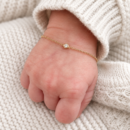 Illustrative newborn bracelet with a fine chain and single stone on a baby wrist