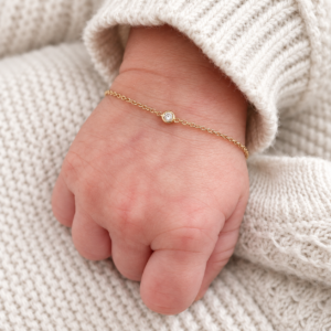 Illustrative newborn bracelet with a fine chain and single stone on a baby wrist